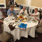 residents of a senior living community sit around a table enjoying drinks