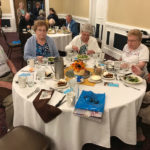 residents of a senior living community sitting together around a table enjoying drinks