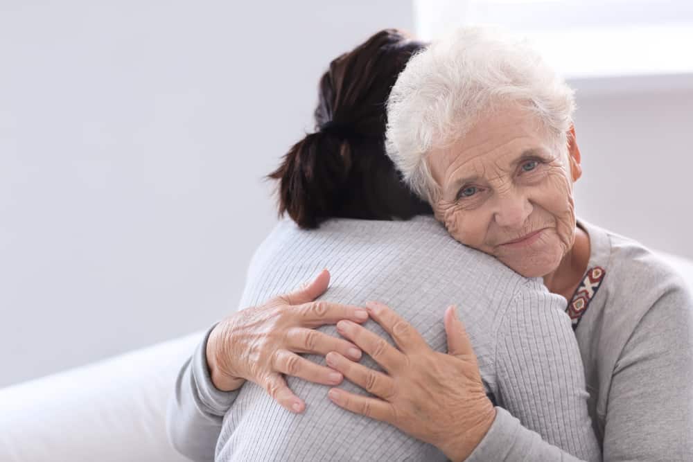 A woman and elderly woman hugging - showing the elderly woman's face